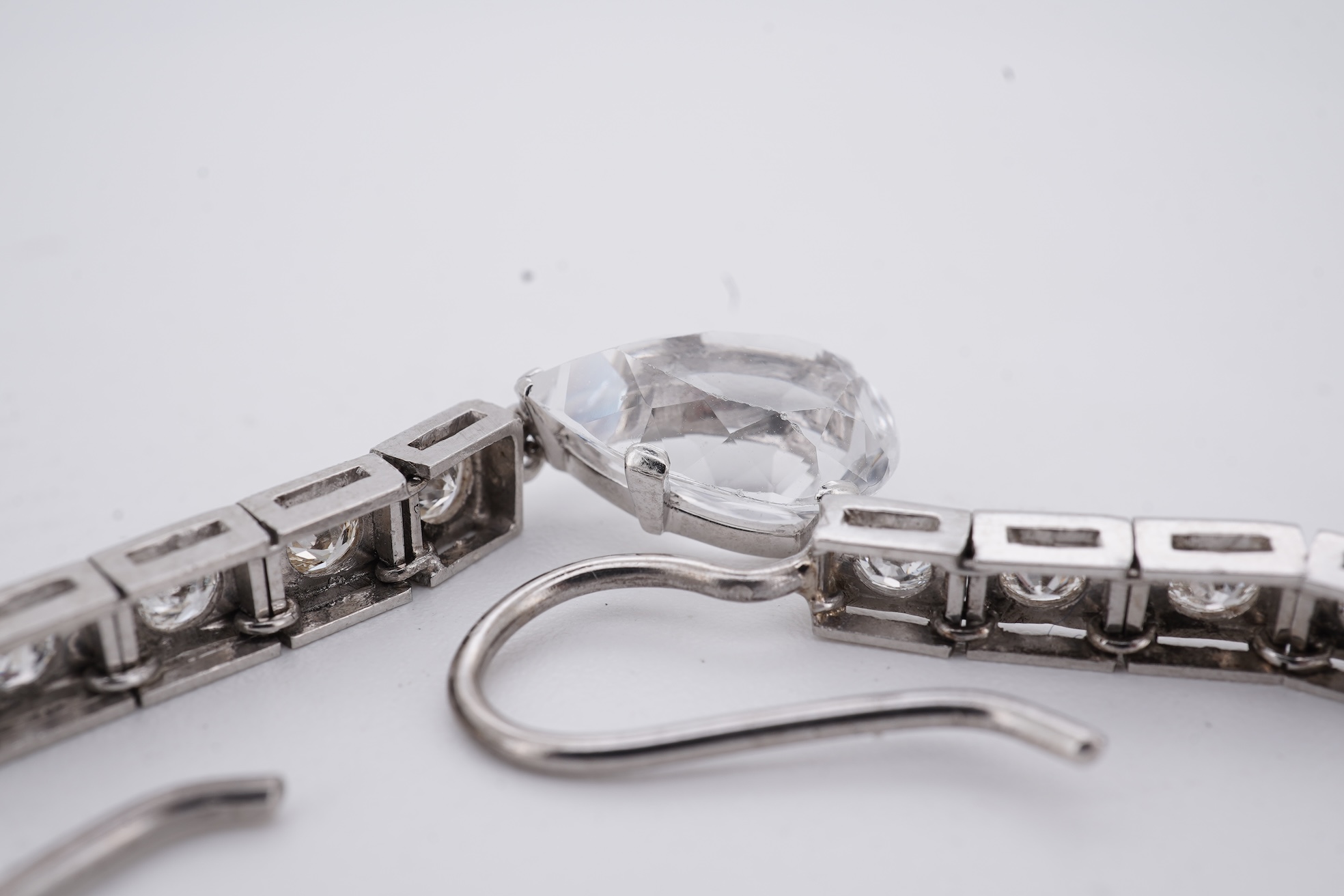 A pair of white metal and four stone diamond set earrings, each with a cubic zirconia pear shaped drop, overall 42mm.